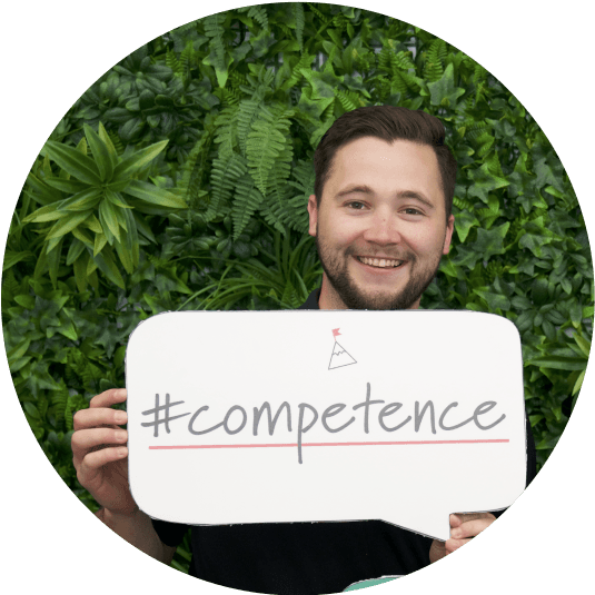 Cole Horton, Sales Enablement Specialist, holding #competence sign